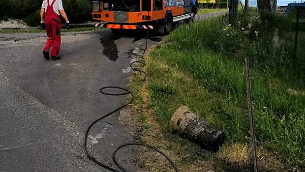 Pracovník jde k uliční vpusti, hadice je vedená od tlakového vozu